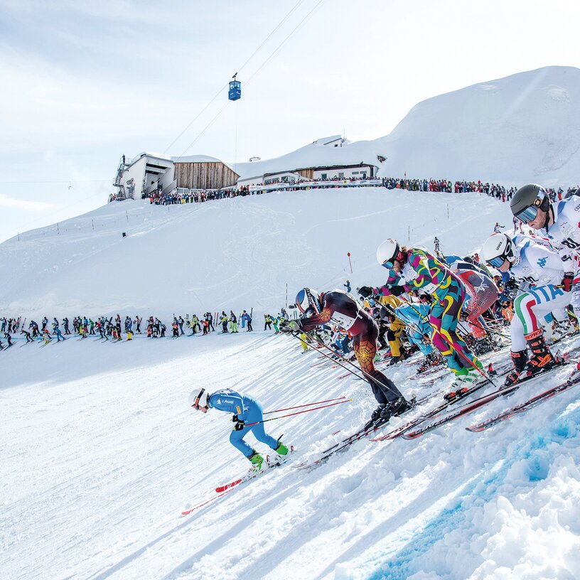 Skifahrer beim Massenstart auf einer schneebedeckten Piste.