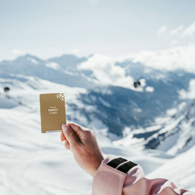 Hand hält Sicherheitskarte mit Bergblick im Hintergrund.
