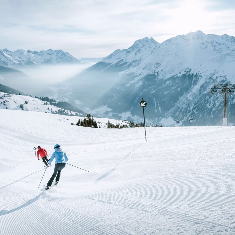 Two people skiing on a snowy slope in the Alps.