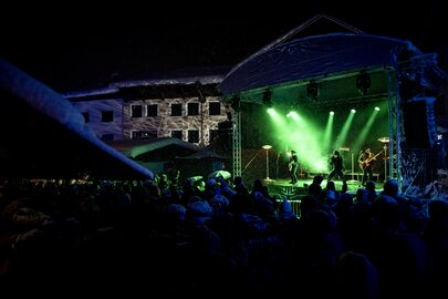 Crowd in front of a stage during a night concert with green lighting.
