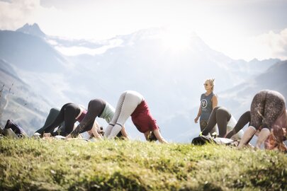 Gruppe praktiziert Yoga in den Alpen unter Anleitung im Freien.