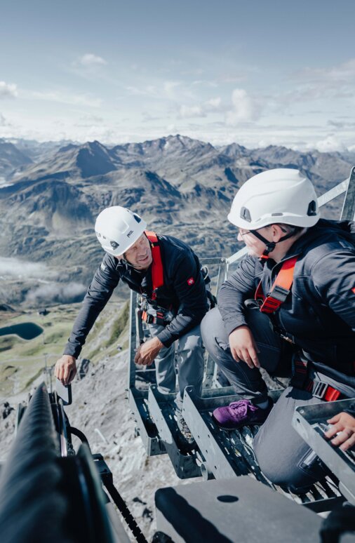 Two men carry out a technical inspection of a cable car system in St. Anton in the summer.