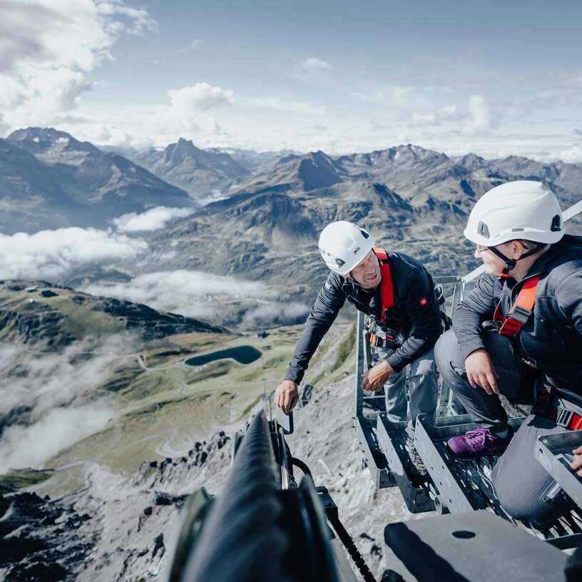 Zwei Männer führen im Sommer eine technische Überprüfung einer Seilbahnanlage in St. Anton durch.