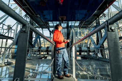 Mann im roten Pullover überprüft Mechanik in Seilbahnstation.