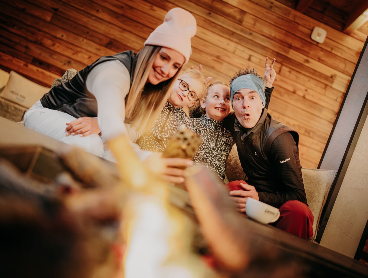 Family taking a selfie in front of a fireplace in a mountain lodge.