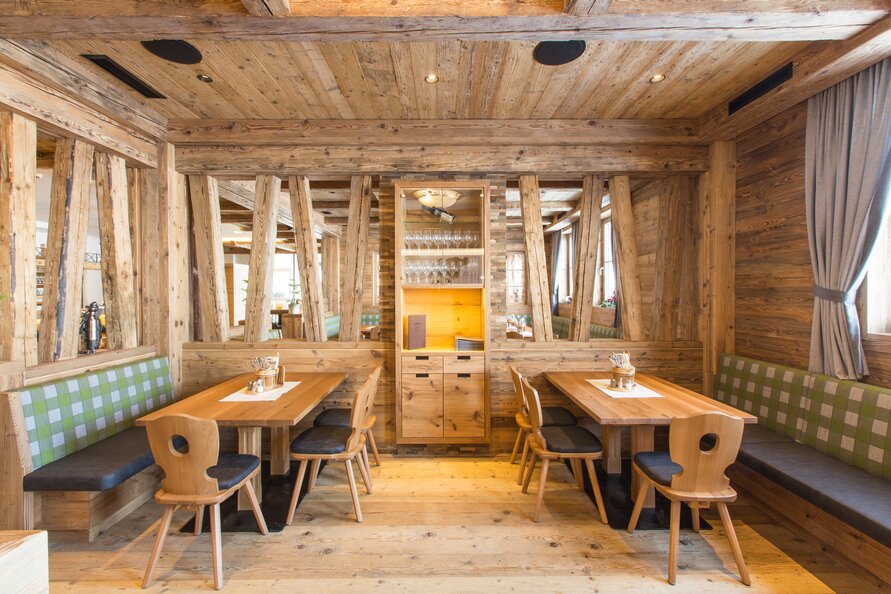 A restaurant with wooden decor, wooden tables, and green checkered upholstery.