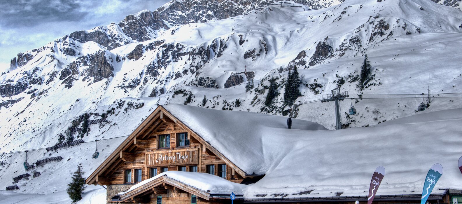 Snowy alpine lodge with skiers and mountain backdrop.