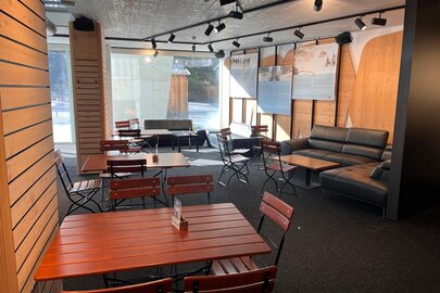 Einladender Raum mit Holztischen und modernen Sofas im Bistro Rauz.