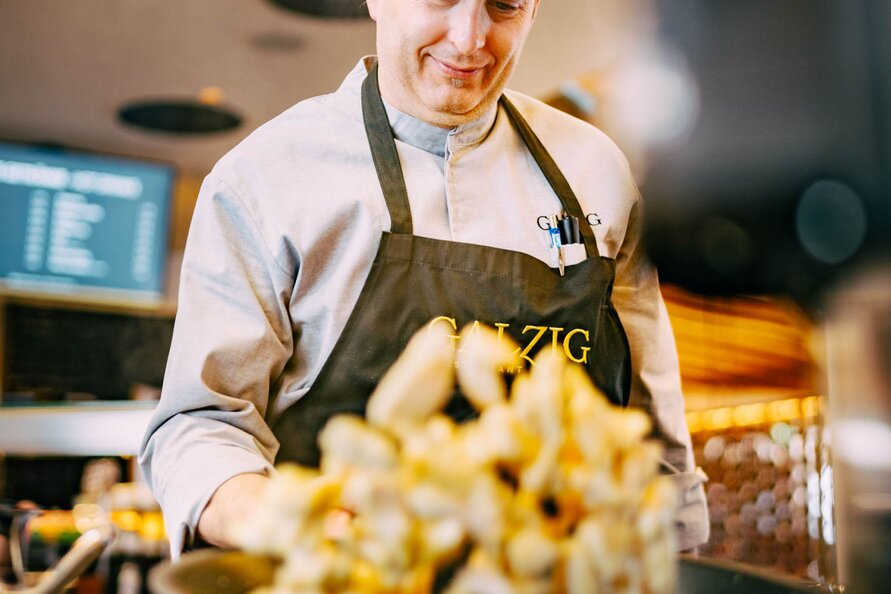 A chef at Galzig Restaurant tossing food in a pan.