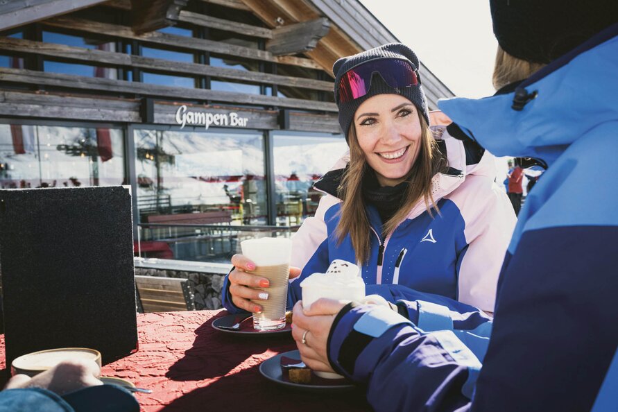 Person enjoying hot beverages in front of Gampen Restaurant in the snow.