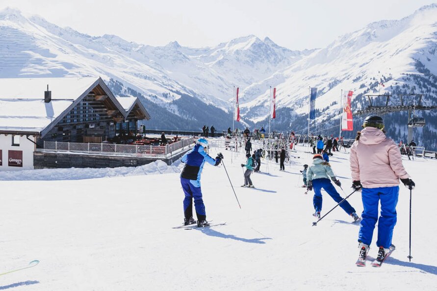 Skiers in snowy mountain setting at Gampen Restaurant, sunny day.