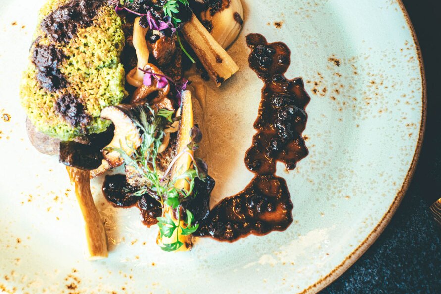 Artfully arranged dish at Restaurant Himmeleck on a white plate with sauce decoration.