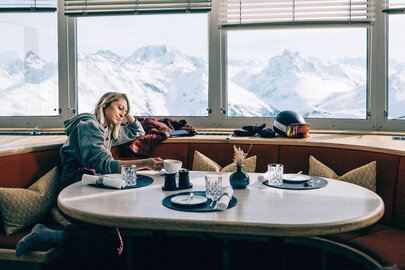 A woman enjoys the view at restaurant Valluga View with snow-covered mountains in the background.
