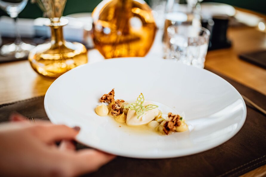 A carefully plated dessert at Verwallstube on a white plate, garnished with crunchy elements and sweet details.