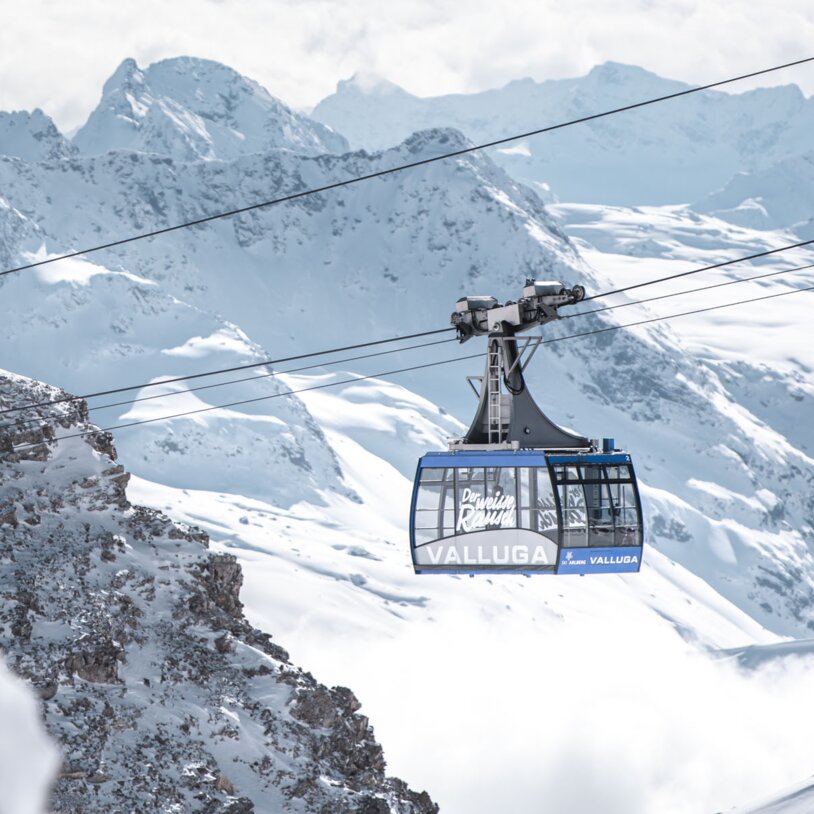 A cable car traveling through a winter alpine landscape.