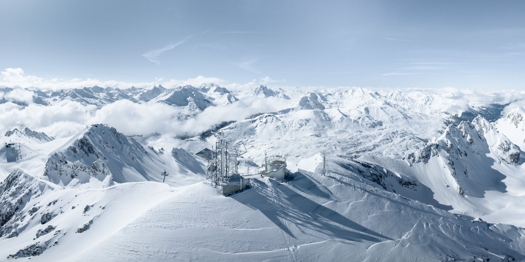 Snowy mountains under a blue sky with bright sunshine.