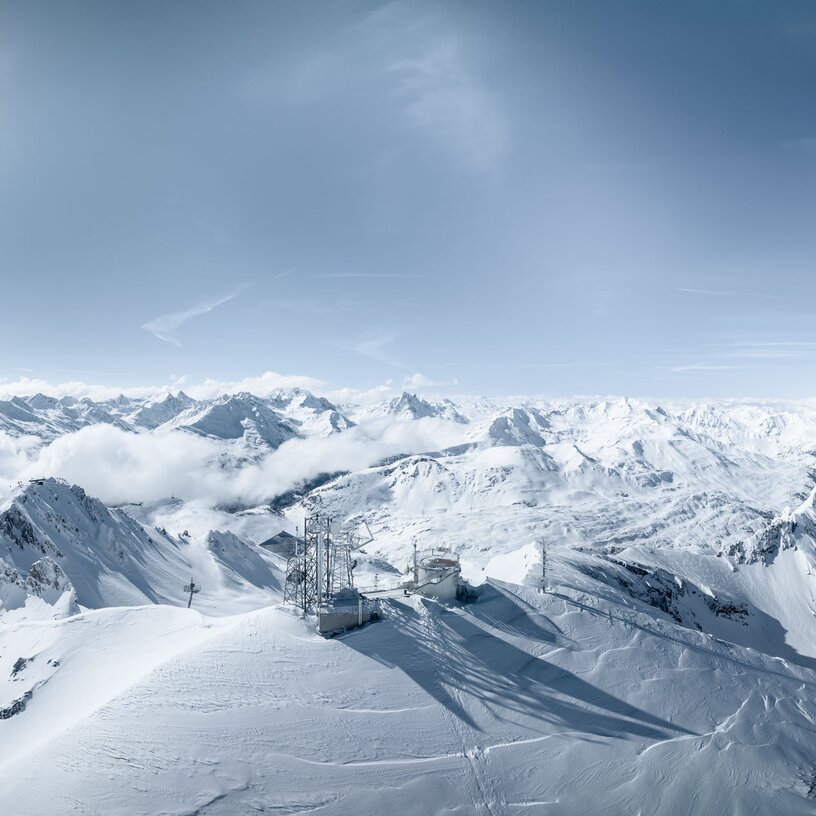 Snowy mountains under a blue sky with bright sunshine.