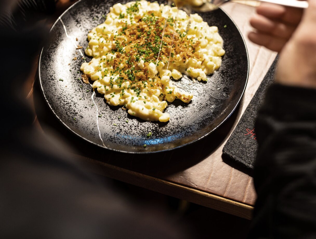 Traditional "Kasnocken" garnished with herbs on a black plate.