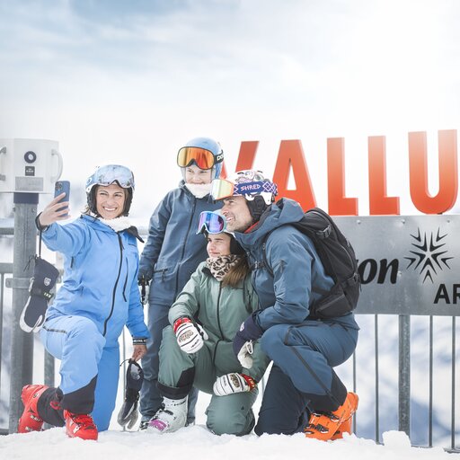 Familie macht Selfie auf der Valluga mit Skiausrüstung im Schnee.