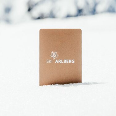 A Ski Arlberg ski pass in the snow, Alpine peaks in the background.