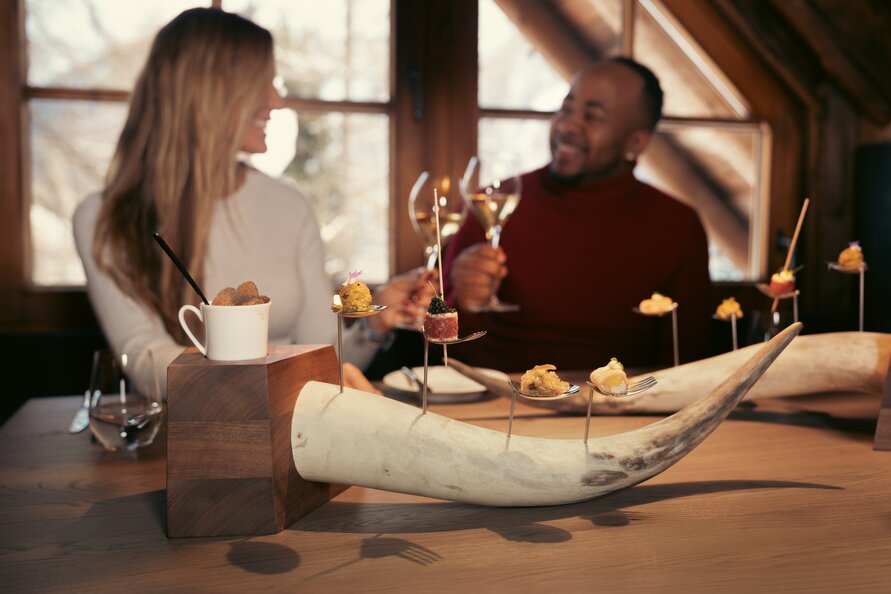 Couple enjoying exquisite food and drinks in rustic setting.