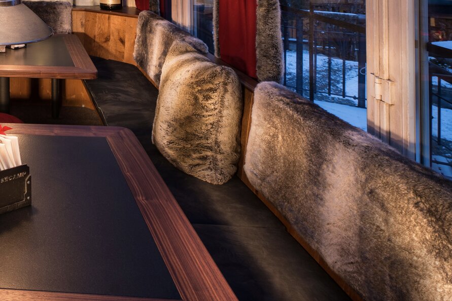 Essbereich mit Fellkissen und Holzdekoration bei gedimmtem Licht.