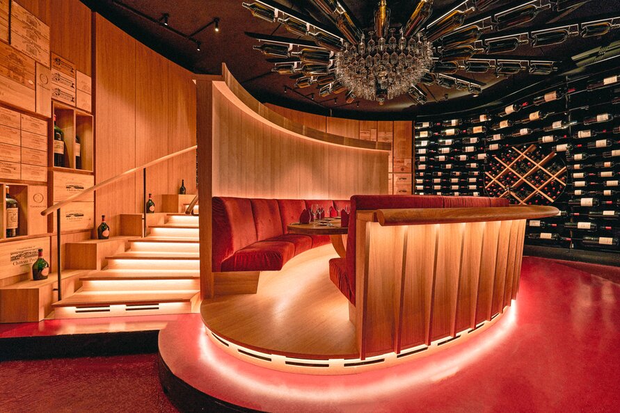 Round seating area in wood design with wine racks and stylish lighting.