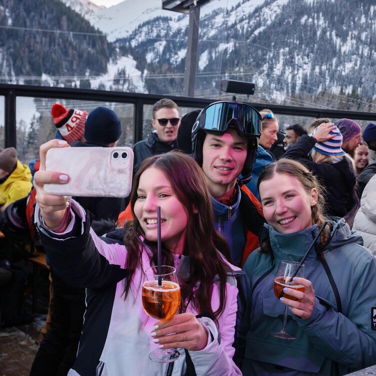 Group of young people taking a selfie at a ski lodge.