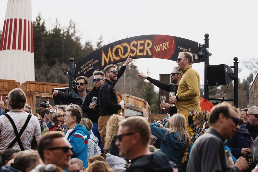 People celebrating and dancing in front of MooserWirt sign.
