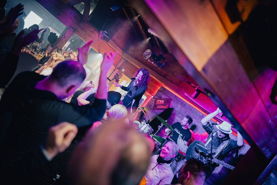 People cheering for a band performing live in a bar.