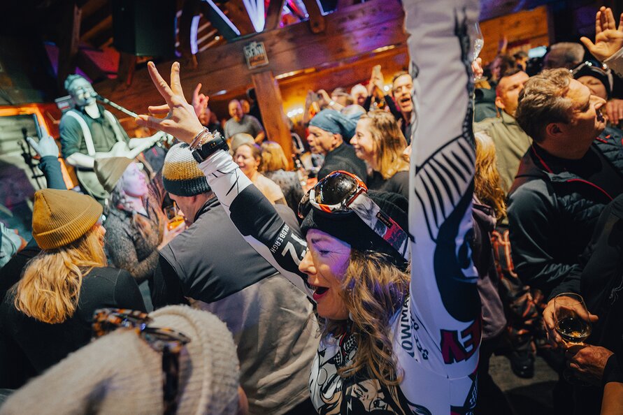 People dancing energetically in a crowded ski lodge.