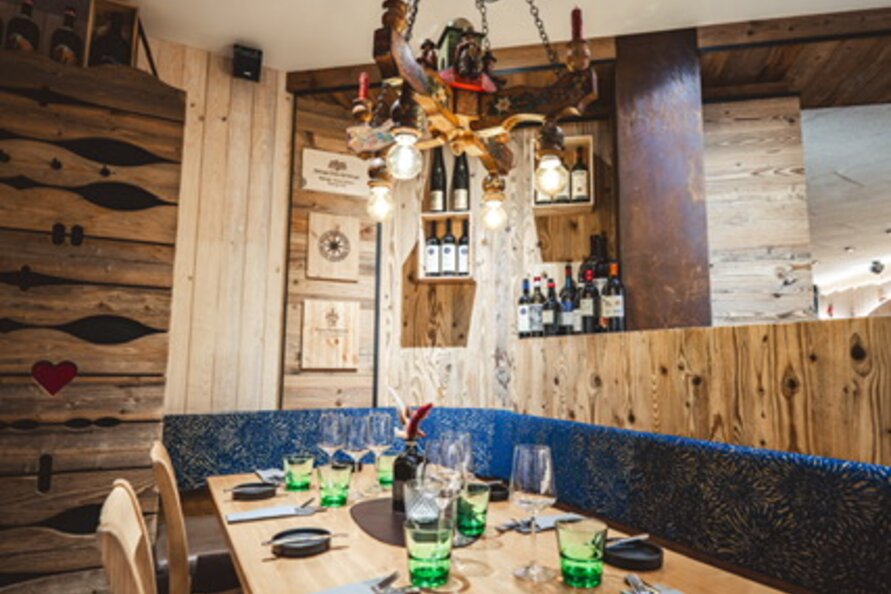 A rustic table in a restaurant decorated with wood elements and green glasses.