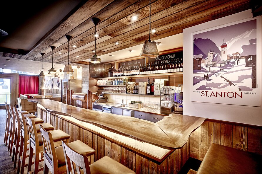Wood-paneled bar with seating and Alpine poster on the wall.