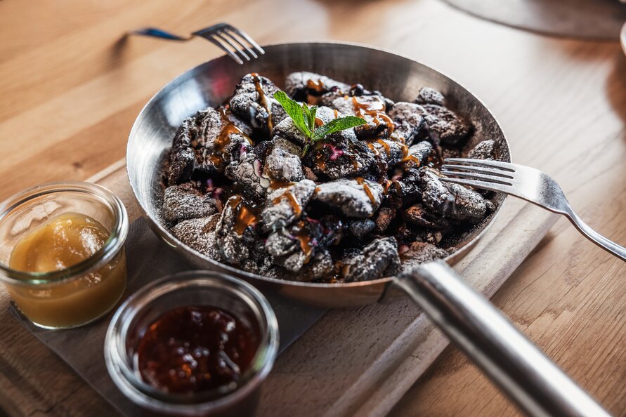 Baked dessert with sugar and mint, served in a pan with two little bowls of fruit sauce.
