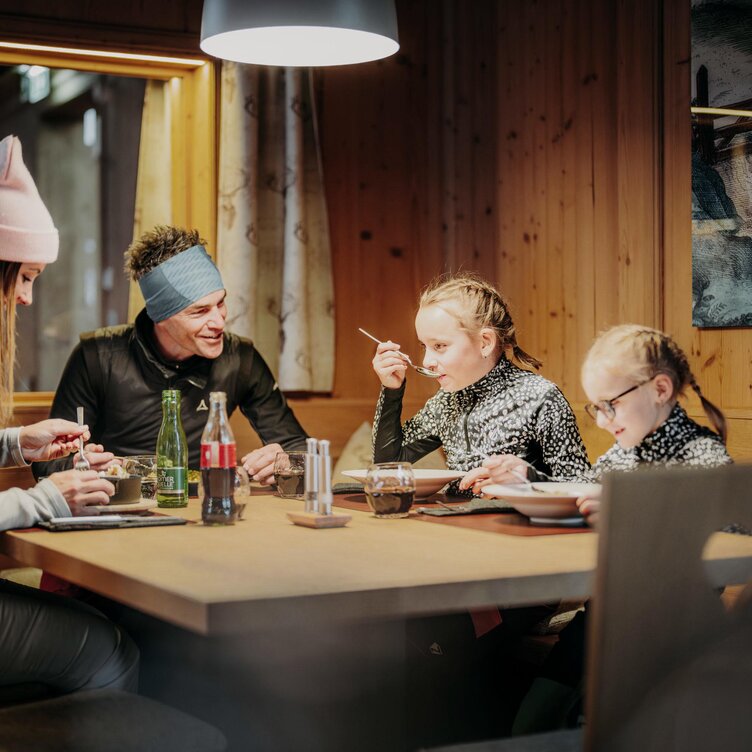 Family dining together at a table in a wooden cabin.