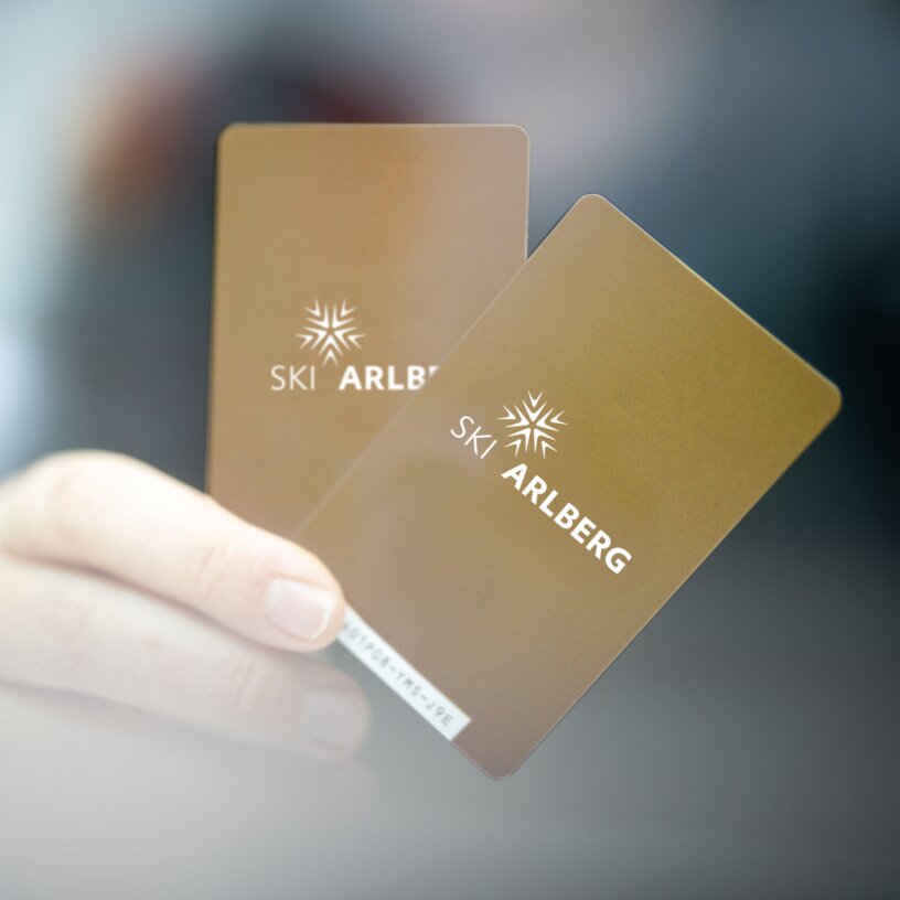 Two Ski Arlberg passes held in a hand.