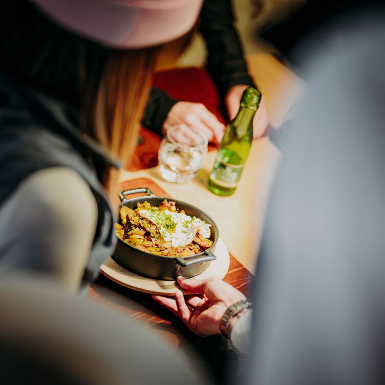 People eating from a pan and drinking mineral water.