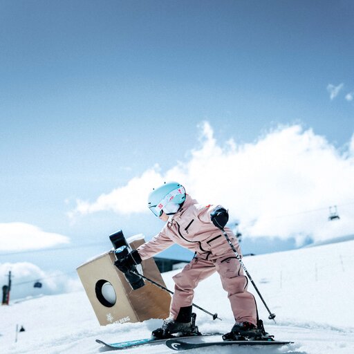 Child on skis with helmet balancing next to a sculpture in snow.