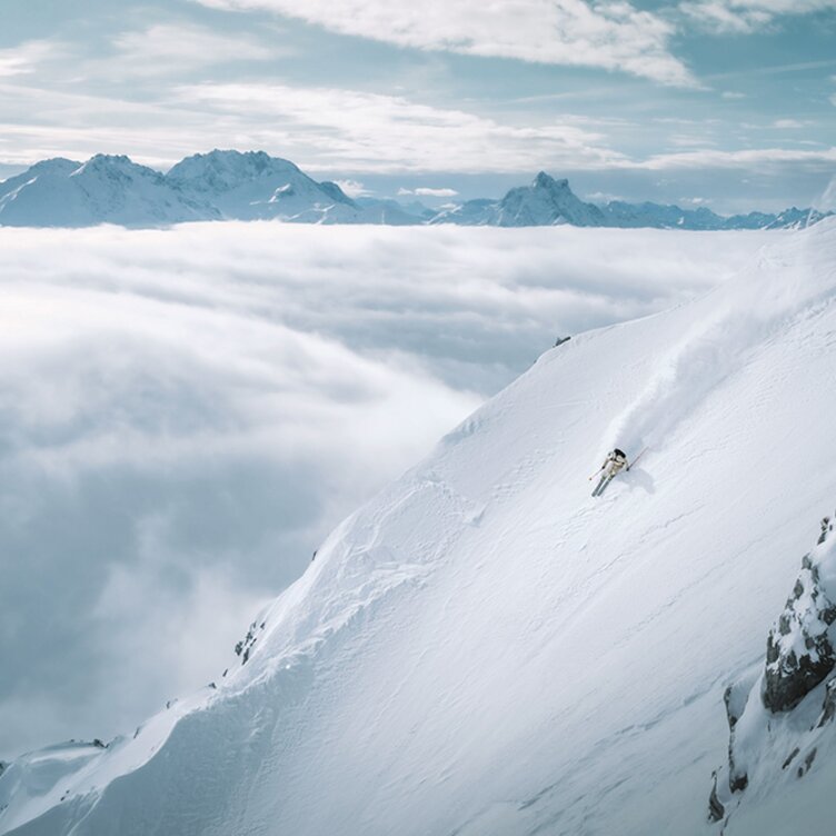 Skier descending a steep, snow-covered slope.