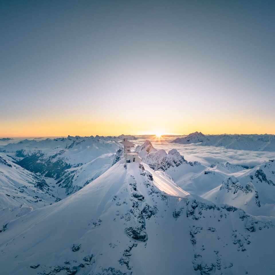 View of snow-covered mountain peaks and sunrise, stunning winter landscape.