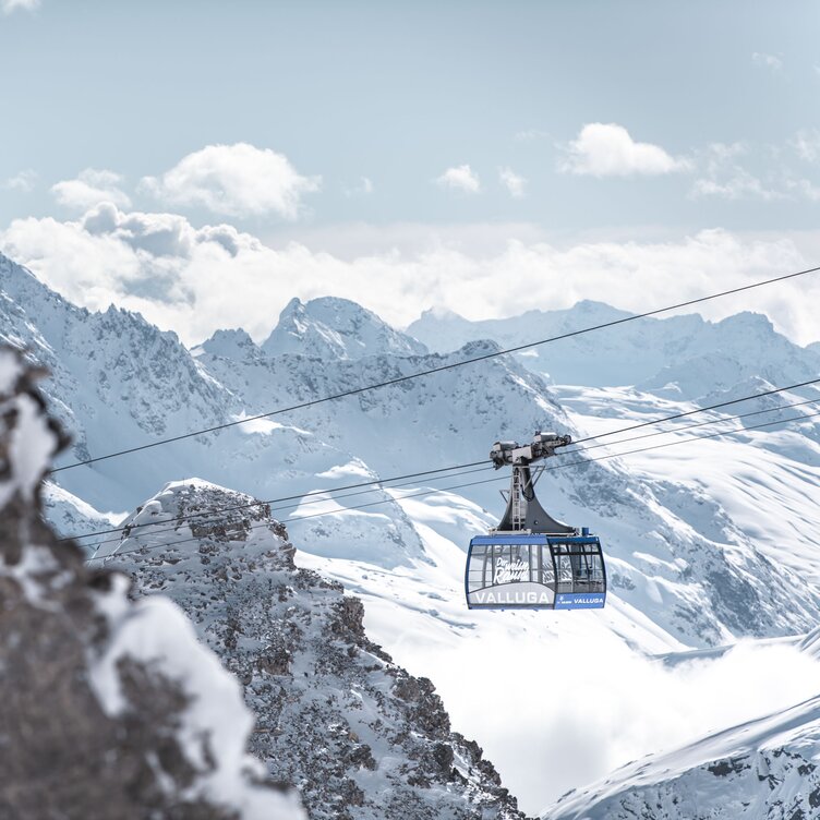 Cable car traveling through snowy Alpine landscape with mountain peaks.