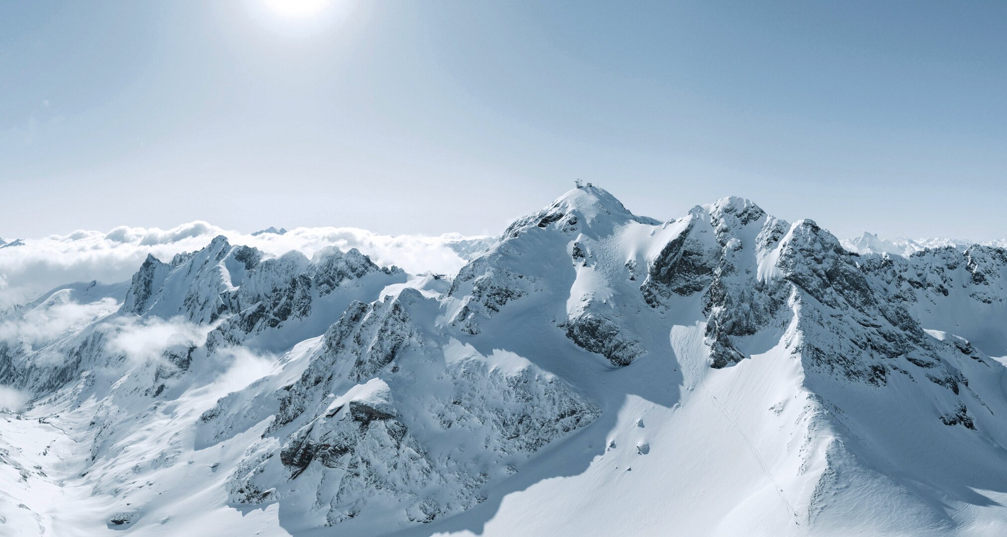 Verschneite Alpenlandschaft mit majestätischen Bergen im Sonnenschein.