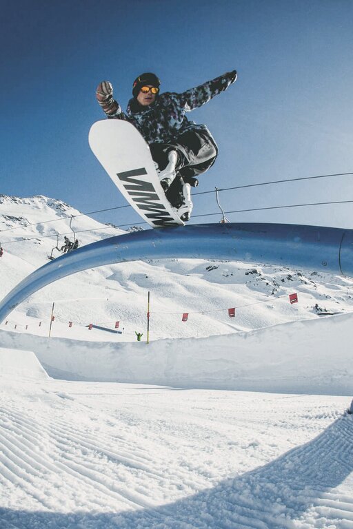Ein Snowboarder slidet über einen blauen Railbogen im stanton park.