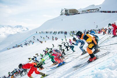 Skifahrer in bunten Outfits starten die Abfahrt des Skirennens der Weisse Rausch am Arlberg.