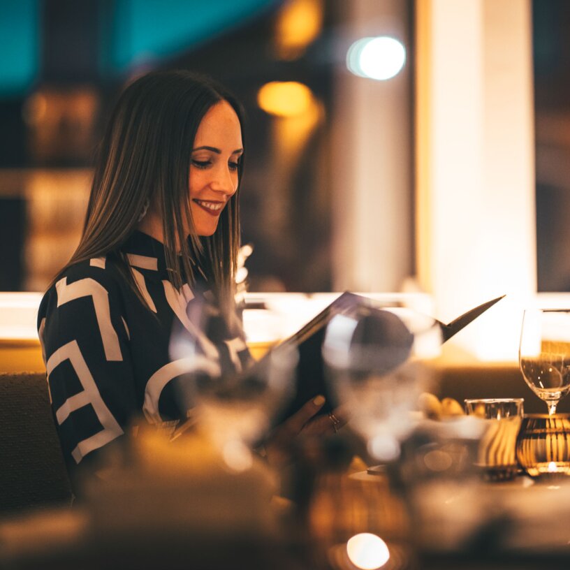 Woman enjoying a candlelight dinner in an elegant setting.
