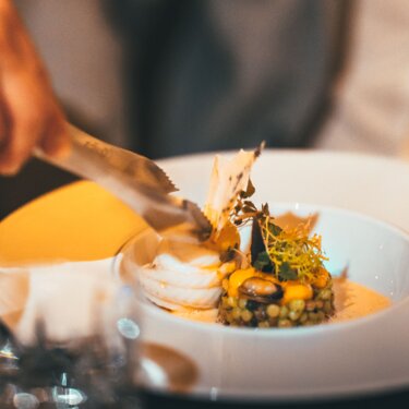Person enjoying a stylishly presented dish by candlelight.