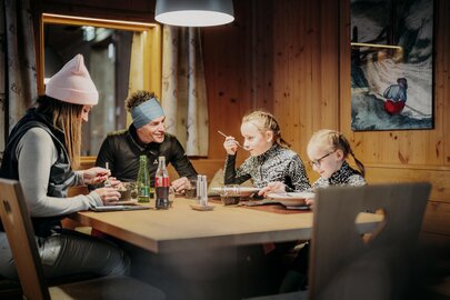 Familie genießt Abendessen in einer Skihütte nach dem Rodeln.