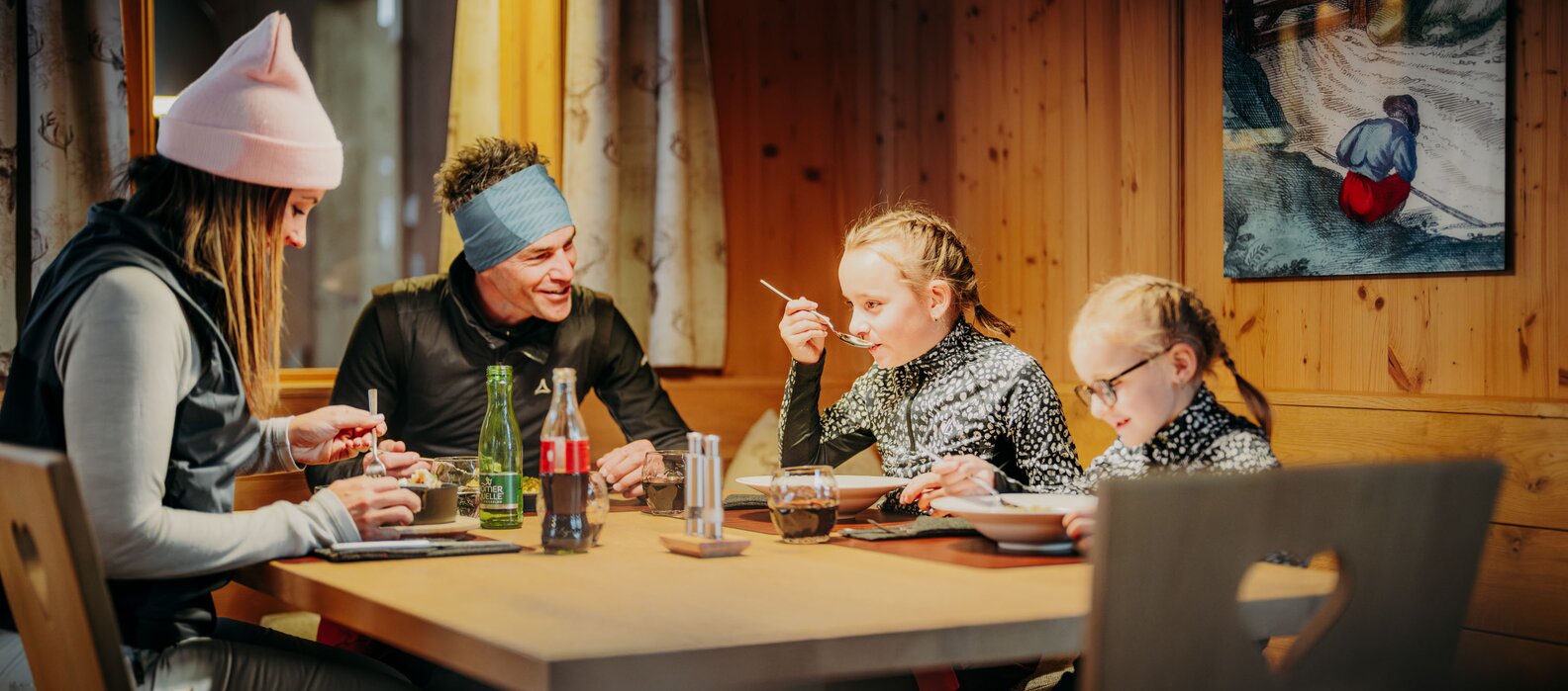 Family dining together at a wooden table in a mountain lodge.
