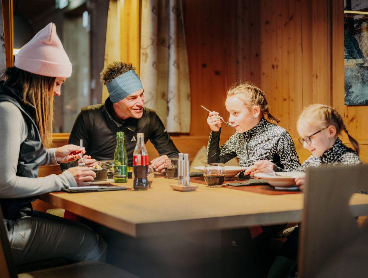 Family dining together at a wooden table in a mountain lodge.