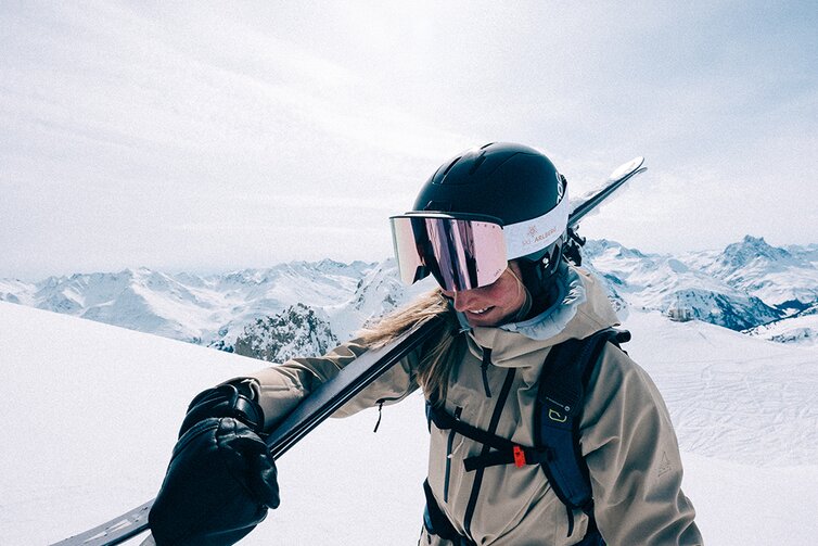 Person with skis and gear on snowy mountain peak.